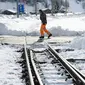 Seorang petugas memeriksa kondisi rel kereta api yang tertutup salju tebal di salah satu resor ski paling populer di Swiss (10/1). Sekitar 13.000 wisatawan terjebak akibat bencana tersebut. (AFP Photo/Fabrice Coffrini)