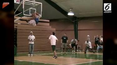 Seorang pemain basket tersangkut di ring usai melakukan dunk ke keranjang tim lawan. Bagian tubuh yang tersangkut jaring ring itu adalah kakinya.
