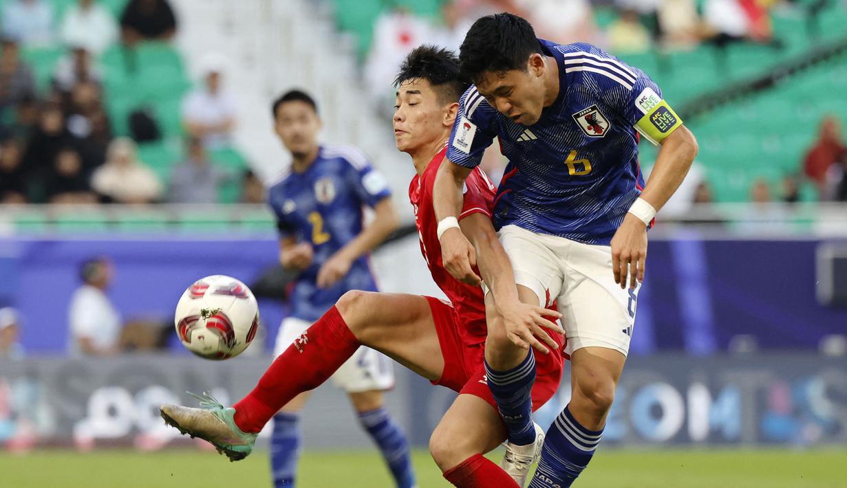 Pemain Vietnam, Nguyen Dinh Bac (kiri) berebut bola dengan pemain Jepang, Wataru Endo pada laga Grup D Piala Asia 2023 di Al Thumama Stadium, Qatar, Minggu (14/01/2024). (AFP/Karim Jaafar)