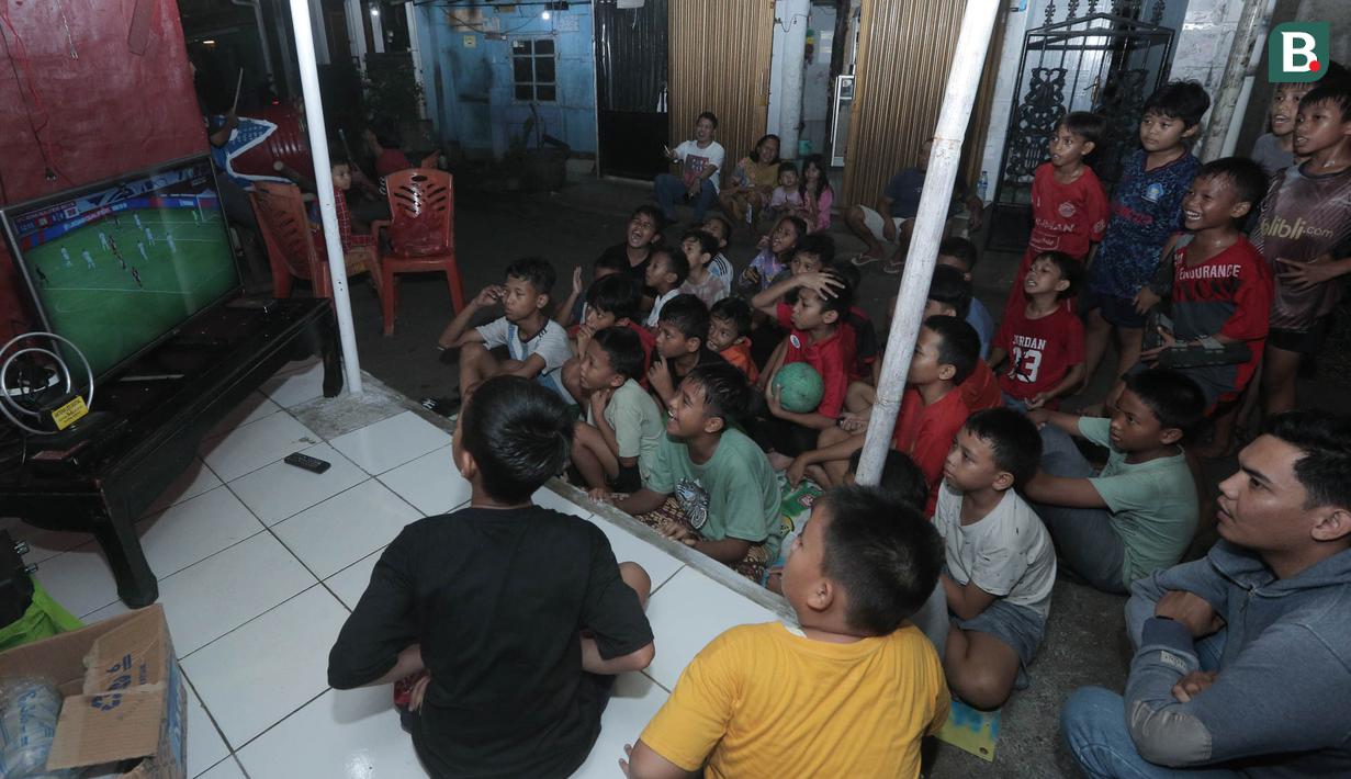 Sejumlah warga tampak tegang saat menyaksikan laga Timnas Indonsia melawan Bahrain dalam pertandingan Grup C putaran ketiga Kualifikasi Piala Dunia 2026 zona Asia di kawasan Menteng Jaya, Jakarta, Selasa (25/5/2025). (Bola.com/M Iqbal Ichsan)