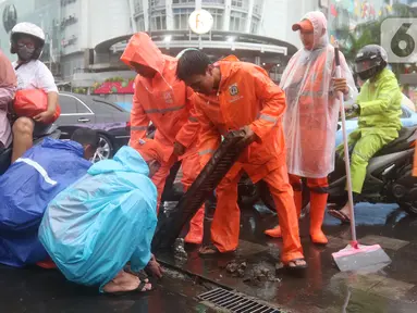 Petugas Penanganan Prasarana dan Sarana Umum (PPSU) membersihkan saluran air di kawasan Gelora Bung Karno, Jakarta, Selasa (17/12/2019). Petugas PPSU membersikan saluran air saat terjadi genangan usai hujan deras mengguyur Jakarta. (Liputan6.com/Herman Zakharia)