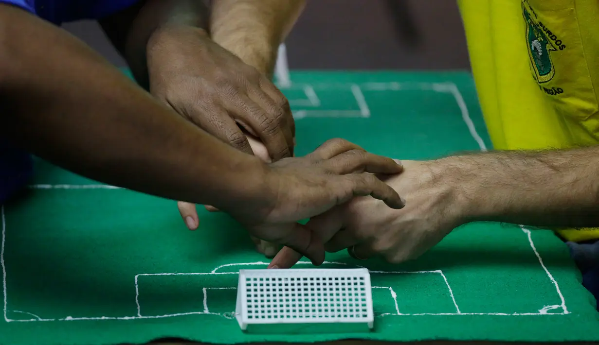 Carlos Junior merasakan pertandingan 16 besar Piala Dunia 2018 di Sao Paulo, Brasil, (2/7). Penerjemah menggunakan komunikasi sentuhan dan miniatur lapangan sepak bola untuk menceritakan dalam pertandingan tersebut. (AP Photo / Nelson Antoine)
