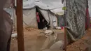 Nanaa Abu Jari memasak di luar tendanya setelah tenda tersebut terendam air hujan di Nuseirat, Jalur Gaza tengah, Jumat, 2 Januari 2026. Hingga awal Januari 2026, wilayah Gaza masih dihantam cuaca ekstrem yang memperparah krisis kemanusiaan di sana. (AP Photo/Abdel Kareem Hana)