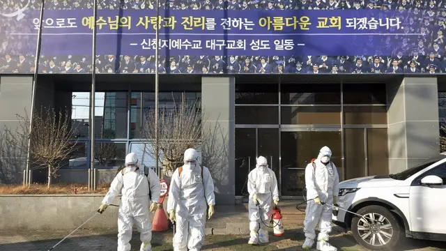 Para pekerja yang mengenakan pakaian pelindung menyemprotkan desinfektan terhadap virus corona baru di depan sebuah gereja di Daegu, Korea Selatan, Kamis, 20 Februari 2020.