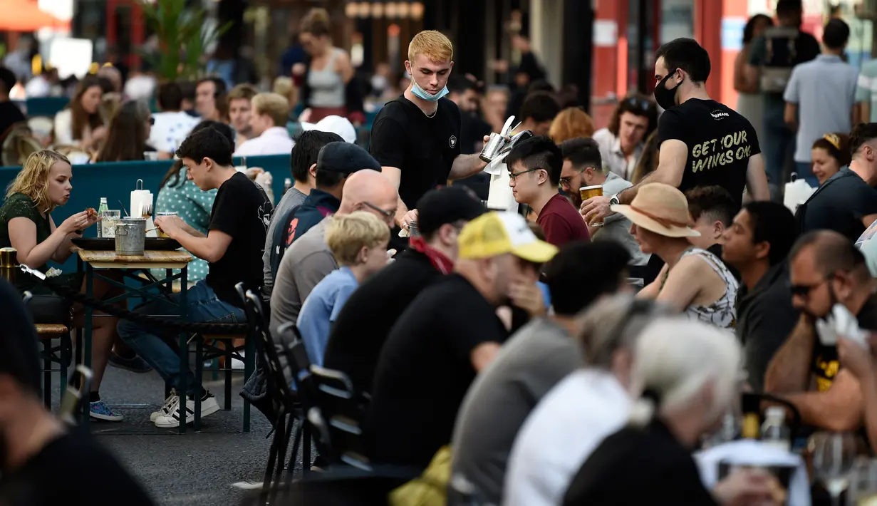 Pelanggan menikmati makan siang di meja di luar restoran di Soho, London, ketika pemerintah Inggris mempertimbangkan pembatasan baru pada Minggu (20/9/2020). Inggris kemungkinan akan kembali memberlakukan tindakan lockdown akibat lonjakan tajam infeksi virus corona COVID-19. (DANIEL LEAL-OLIVAS/AFP)