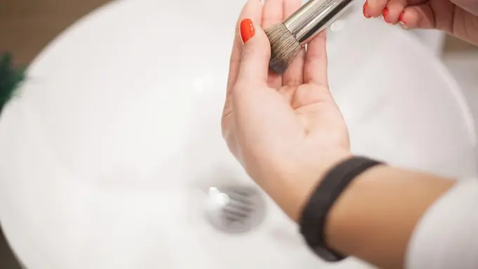 Seorang perempuan sedang mencuci brush makeup di wastafel (Foto Dok: Freepik/maksymiv_yura)