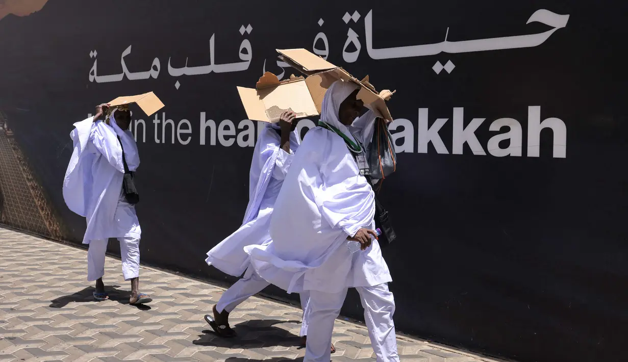 Umat muslim menggunakan karton untuk melindungi diri dari sengatan matahari saat berjalan di jalanan di kota Makkah, Arab Saudi, pada 2 Juni 2025. (HAZEM BADER/AFP)