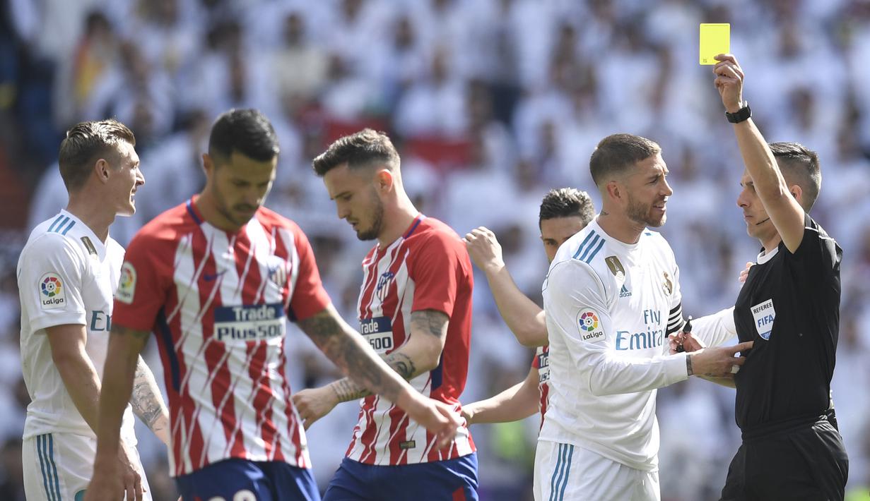 Wasit Xavier Estrada memberikan kartu kuning kepada gelandang Real Madrid, Toni Kross, saat melawan Atletico Madrid pada laga La Liga Spanyol di Stadion Santiago Bernabeu, Madrid, Minggu (8/4/2018). Kedua klub bermain imbang 1-1. (AFP/Gabriel Bouys)