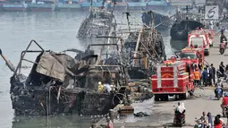Petugas pemadam kebakaran melakukan pendinginan kapal yang ludes dilalap api di Pelabuhan Muara Baru, Jakarta, Minggu (24/2). Dalam peristiwa tersebut sebanyak tiga orang mengalami sesak napas. (Merdeka.com/Iqbal Nugroho)