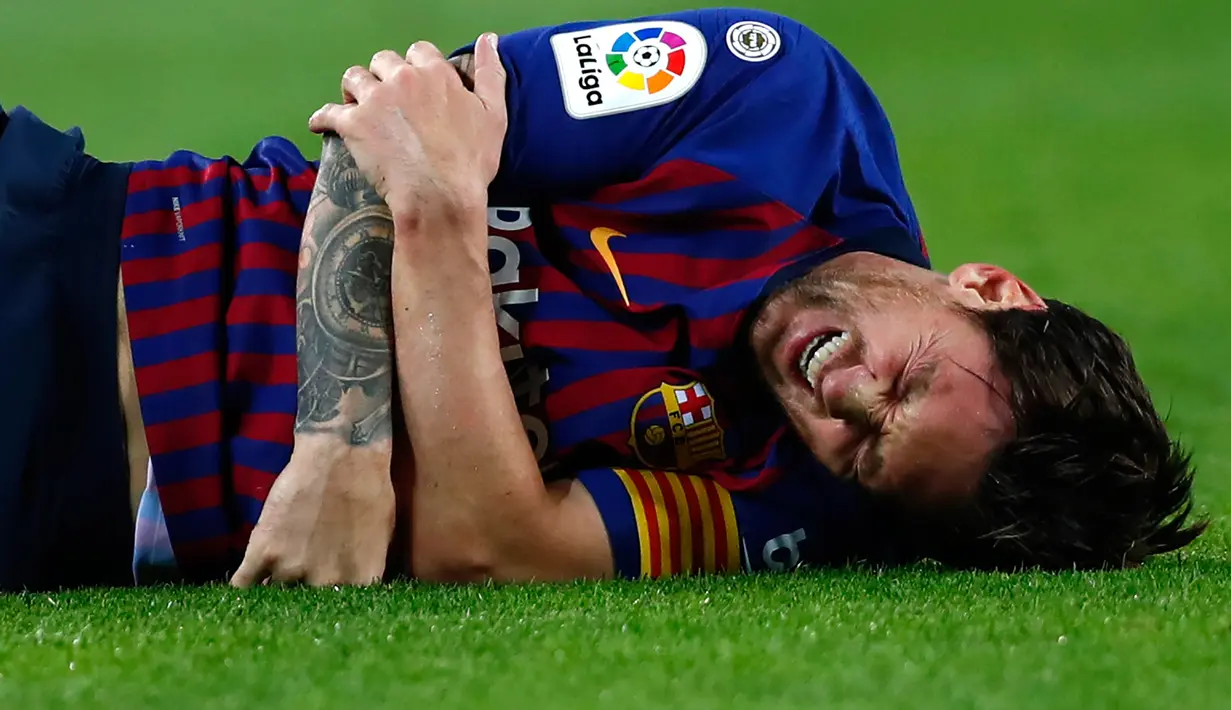 Megabintang Barcelona, Lionel Messi mengerang sambil memegangi sikut kanannya setelah mendarat tak sempurna saat terjatuh dalam lanjutan Liga Spanyol di Stadion Camp Nou, Minggu (21/10). Messi cedera saat Barca mengalahkan Sevilla. (AP/Manu Fernandez)