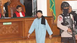 Terdakwa terorisme, Aman Abdurrahman menuju kursi pesakitan pada sidang pembacaan vonis di PN Jakarta Selatan, Jumat (22/6). Sesuai kesepakatan dengan KPI, persidangan tidak boleh disiarkan secara langsung di stasiun TV. (Liputan6.com/Angga Yuniar)