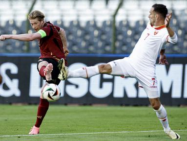 bola dengan bek Montenegro Marko Vesovic dalam duel uji coba internasional jelang Euro 2024 di Stade Roi Baudouin, Brussels, Kamis (6/6/2024). (Kenzo TRIBOUILLARD / Belga / AFP)