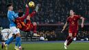 Striker AS Roma, Nicola Zalewski (tengah) berusaha melepaskan tendangan akrobatik di depan bek Napoli, Giovanni di Lorenzo pada laga pekan ke-17 Liga Italia 2023/2024 di Olympic Stadium, Roma, Minggu (24/12/2023) dini hari WIB. (AFP/Tiziana Fabi)