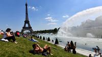 Warga berpanas di samping air mancur di Trocadero Esplanade, dekat Menara Eiffel, Paris (8/5). Kebun Trocadero Esplanade memiliki luas 93.930 meter persegi (23,21 hektar). (AFP Photo/Gerard Julien)