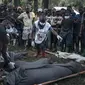 Relawan Palang Merah Kongo dan penduduk Nyamukubi membungkus jenazah orang yang tewas dalam banjir besar di bagian timur Republik Demokratik Kongo dengan selimut, pada 6 Mei 2023. (AFP)