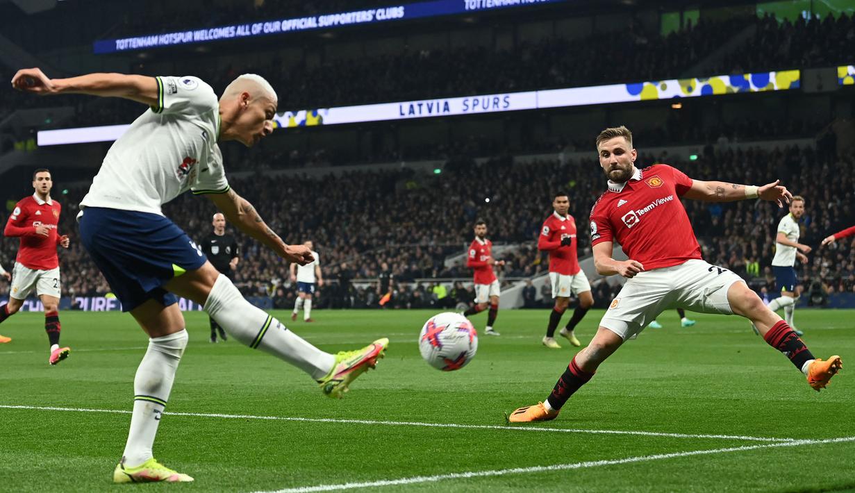 Pemain Tottenham Hotspur, Richarlison (kiri) memberikan umpan silang dibayangi pemain Manchester United, Luke Shaw pada laga pekan ke-33 Liga Inggris 2022/2023 di Tottenham Hotspur Stadium, London, Jumat (28/04/2023) WIB. Laga berakhir dengan skor 2-2. (AFP/Glyn Kirk)