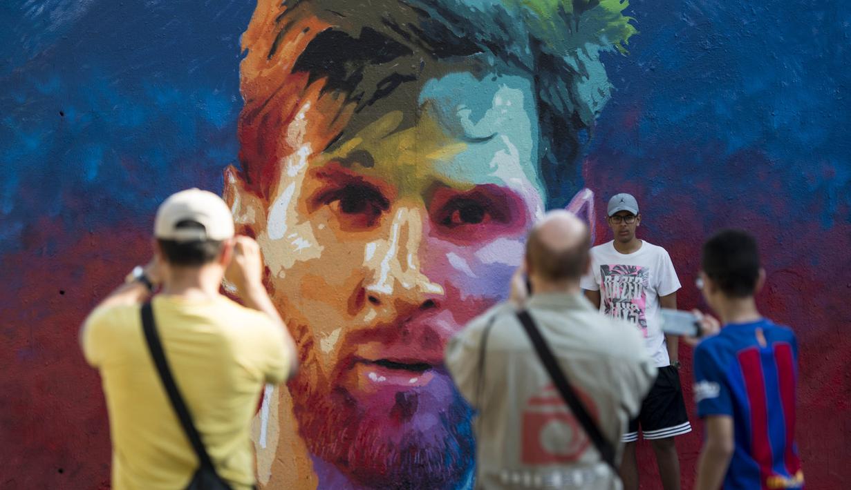 Warga foto di depan mural bergambar wajah bintang Barcelona, Lionel Messi, di Barcelona, Catalonia, Sabtu (17/6/2017). (AFP/Josep Lago)