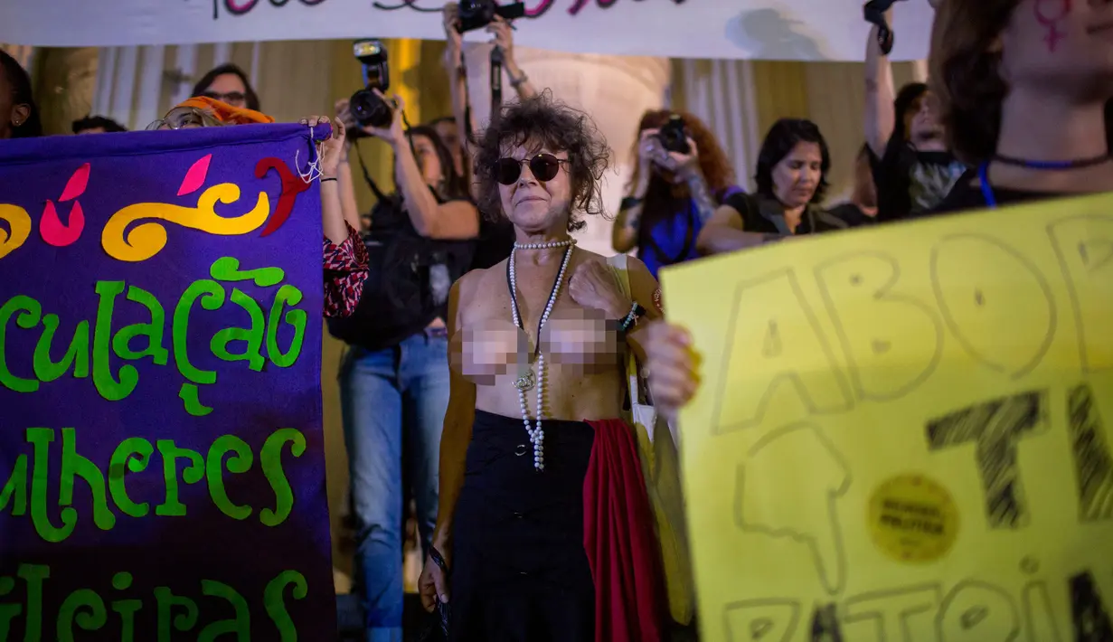 Seorang wanita bertelanjang dada saat mengikuti protes pelarangan aborsi di Rio de Janeiro, Brasil (13/11). Para demonstran ini meminta aborsi dilegalkan dalam kasus pemerkosaan dan kehamilan yang mengancam kehidupan. (AFP Photo/Mauro Pimentel)