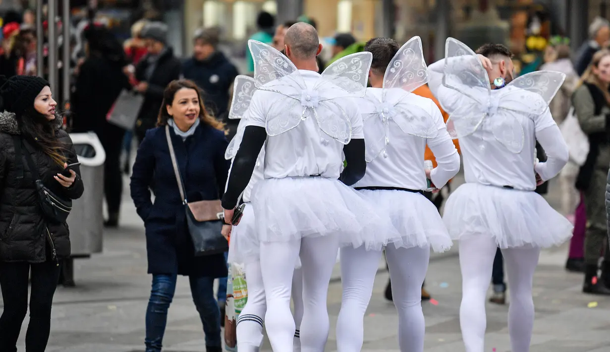 Sekelompok pria mengenakan kostum di jalanan pusat perbelanjaan saat puluhan ribu orang menyambut dimulainya musim karnaval di jalan-jalan Kota Cologne, Jerman, Senin (11/11/2019). Musim karnaval ini dikenal juga sebagai musim kelima dalam satu tahun. (AP Photo/Martin Meissner)