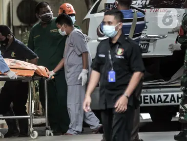 Tim forensik menurunkan kantong jenazah berisi serpihan Sriwijaya Air SJ 182 dan diduga tubuh korban dari ambulans di RS Polri, Jakarta, Minggu (10/1/2021). RS Polri menerima tiga kantong jenazah berisi serpihan pesawat dan diduga tubuh korban untuk diidentifikasi. (merdeka.com/Iqbal S. Nugroho)