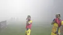 Pemain Persiba Balikpapan  menutup hidung  saat melakukan pemanasan akibat asap flare pada lagaTorabika SC 2016 di Stadion Gelora Bangkalan, Senin(13/6/2016).  (Bola.com/Nicklas Hanoatubun)