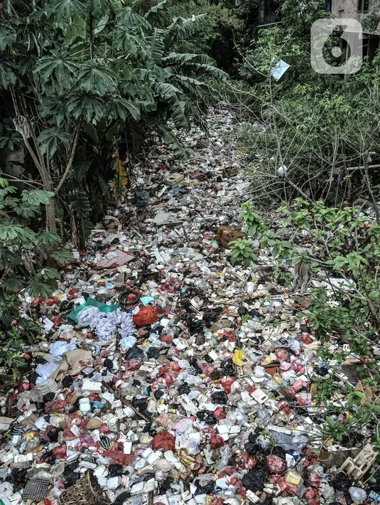 Kondisi tumpukan sampah yang memenuhi aliran Kali Baru, Jalan Raya Bogor, Cimanggis, Depok, Jawa Barat, Minggu (24/1/2021).  Menumpuknya sampah di kawasan perbatasan antara Jakarta dan Depok itu juga diperparah dengan kondisi sungai yang menyempit dan mengalami pedangkalan. (merdeka.com/Iqbal S. Nug