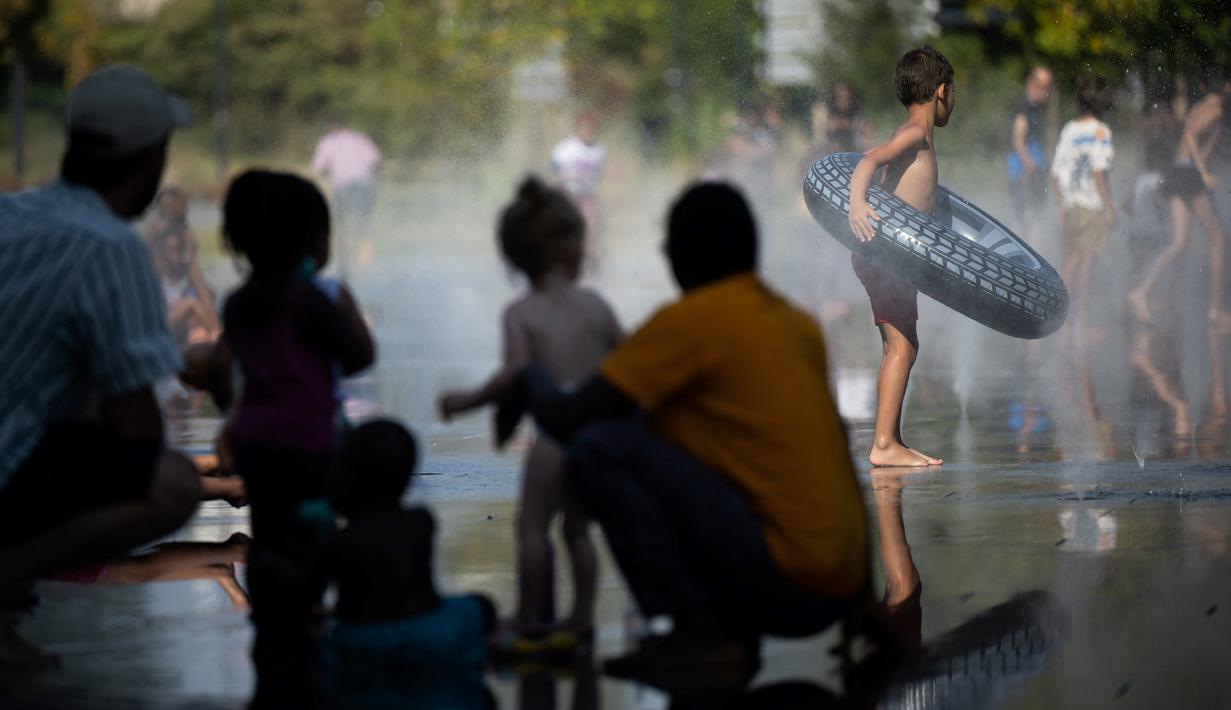 <p>Orang-orang mendinginkan diri dengan air dari pancuran saat suhu udara melebihi 42 derajat celsius di lingkar jalan di Nantes, Senin (18/7/2022). Peramal cuaca menempatkan 15 departemen di sebagian besar sisi barat Prancis ke status siaga tertinggi untuk suhu ekstrem saat gelombang panas melanda negara itu dan akan mencapai puncaknya. (Loic VENANCE / AFP)</p>