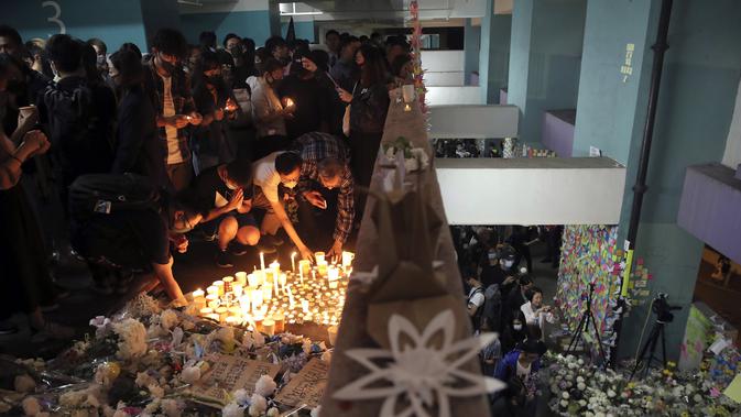 Para pengunjuk rasa menyalakan lilin dan meletakkan bunga di lokasi di mana mahasiswa Alex Chow Tsz-lok jatuh di Hong Kong (8/11/2019). Chow ditemukan terbaring dengan genangan darah di sebuah tempat parkir mobil, yang menjadi sasaran penembakan gas air mata oleh polisi. (AP Photo/Kin Cheung)