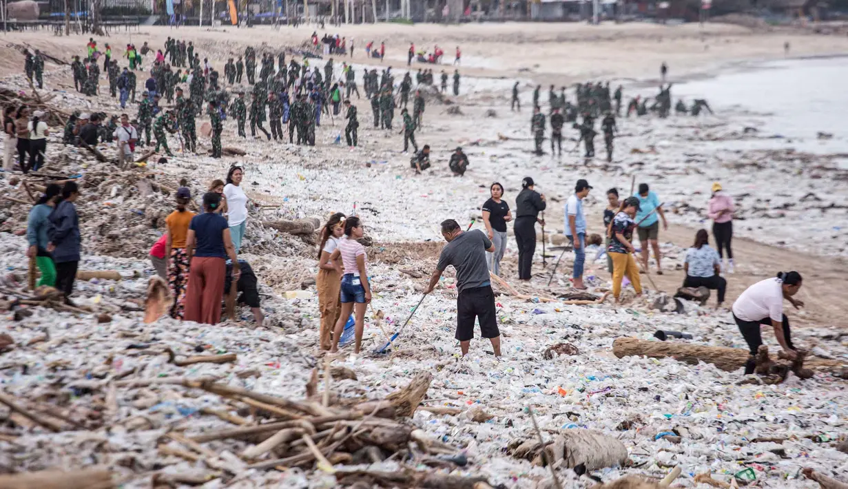 Para pekerja dan warga membersihkan ceceran dan tumpukan sampah plastik yang terdampar di Pantai Jimbaran, Bali, pada Selasa 10 Maret 2026. Pantai Jimbaran, Bali, kembali dipenuhi sampah kiriman. (Lana Priatna/AFP)