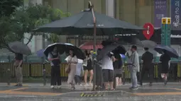 Orang-orang terlihat berdiri di bawah kanopi peneduh saat hujan deras mengguyur di Seoul, Korea Selatan, Rabu, 17 Juli 2024. (AP Photo/Ahn Young-joon)