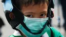 Seorang anak laki-laki mengenakan masker saat dijemput orang tuanya di Bangkok (30/1). Kementerian Kesehatan Thailand memberi peringatan kepada warga dan turis untuk menghindari kegiatan di ruang terbuka dan mengenakan masker. (AP Photo/Sakchai Lalit)