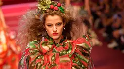 Seorang model berpose di atas catwalk dengan membawa tas besar mirip tas pasar dan mengisinya dengan sayuran untuk koleksi Dolce & Gabbana Spring/Summer 2018 di Milan Fashion Week, Minggu (24/9). (AFP PHOTO / Andreas SOLARO)