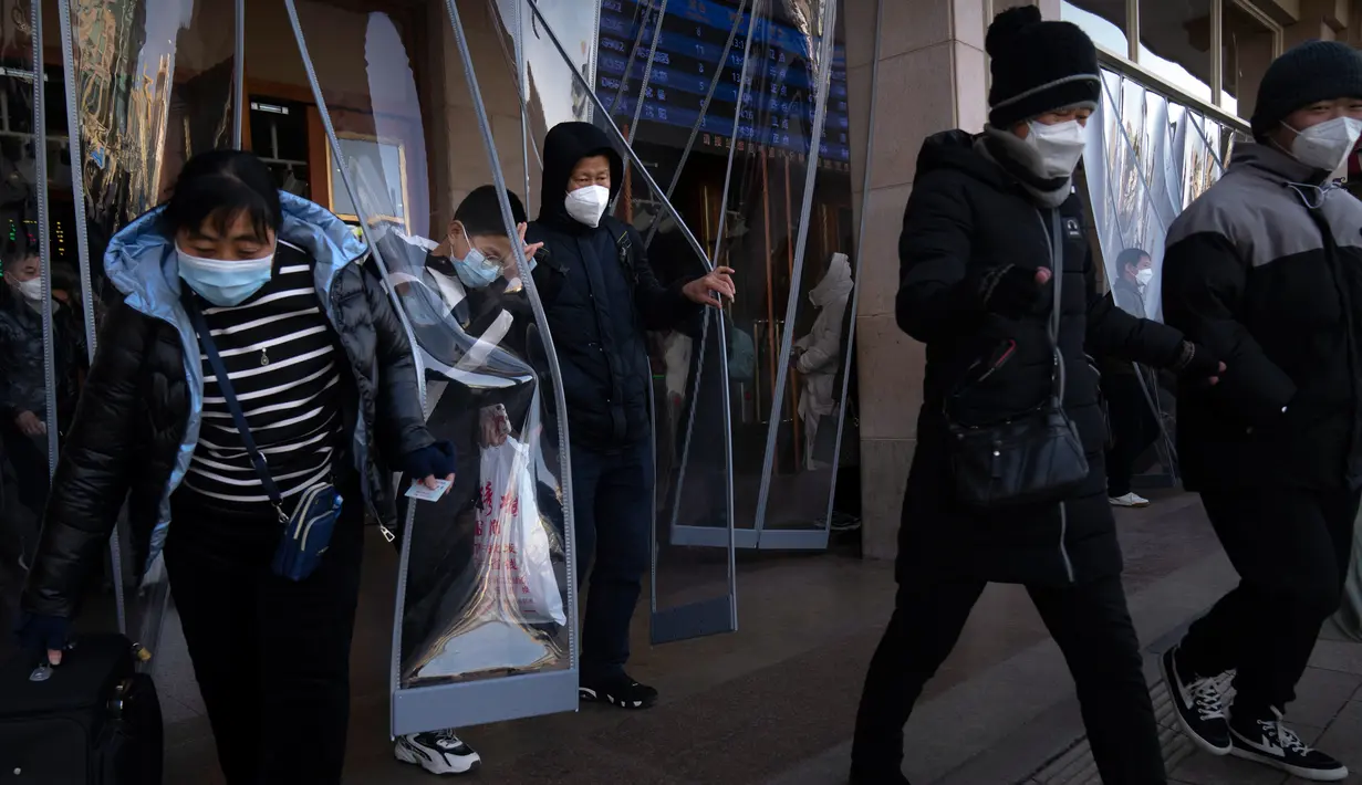 Para pemudik yang memakai masker berjalan keluar dari Stasiun Kereta Api Beijing di Beijing, China, Sabtu (14/1/2023). Jutaan warga China diperkirakan akan melakukan perjalanan selama periode liburan Tahun Baru Imlek tahun ini. (AP Photo/Mark Schiefelbein)
