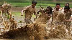 Sejumlah pria Nepal bermain bola di lumpur pada Asar Pandra, atau hari menanam padi nasional di Lalitpur, 29 Juni 2018. Asar Pandra diadakan sebagai tanda dimulainya kembali aktivitas tanam padi di sawah saat musim hujan tiba. (AP Photo/Niranjan Shrestha)