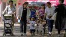 Orang-orang membawa anak-anak mereka ke taman umum selama Hari Anak Internasional di Beijing, China, Selasa (1/6/2021). Para pemimpin China telah mengumumkan akan membiarkan semua pasangan memiliki tiga anak, bukan dua, berharap untuk melawan penuaan cepat masyarakat China. (AP Photo/Andy Wong)