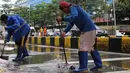 Penanganan dilakukan bersama di lokasi untuk memulihkan kondisi jalan agar kembali aman dan dapat dilalui masyarakat. Tampak dalam foto, petugas Dinas Sumber Daya Air (SDA) DKI Jakarta membersihkan sisa lumpur di Jalan Gunung Sahari Raya atau tepat di depan Mangga Dua Square, Jakarta, Selasa (13/1/2026). (merdeka.com/magang/Rendi Saputra)