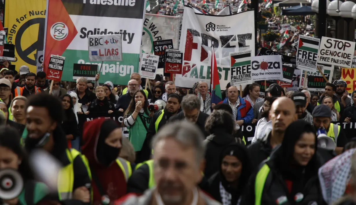 Para pengunjuk rasa mengibarkan bendera dan poster saat demonstrasi pro-Palestina di London, Sabtu, 21 Oktober 2023. (AP Photo/David Cliff)