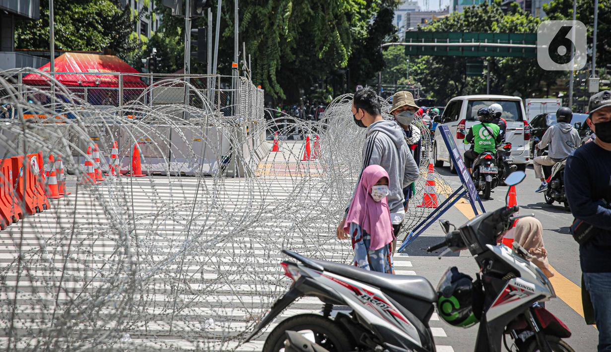 Barikade kawat berduri terpasang di kawasan Jalan MH Thamrin, Jakarta, Kamis (2/12/2021). Polda Metro Jaya memasang barikade di sejumlah titik menuju kawasan Patung Kuda-Monumen Nasional (Monas) Jakarta Pusat guna mengantisipasi kerumunan massa aksi Reuni 212. (Liputan6.com/Faizal Fanani)