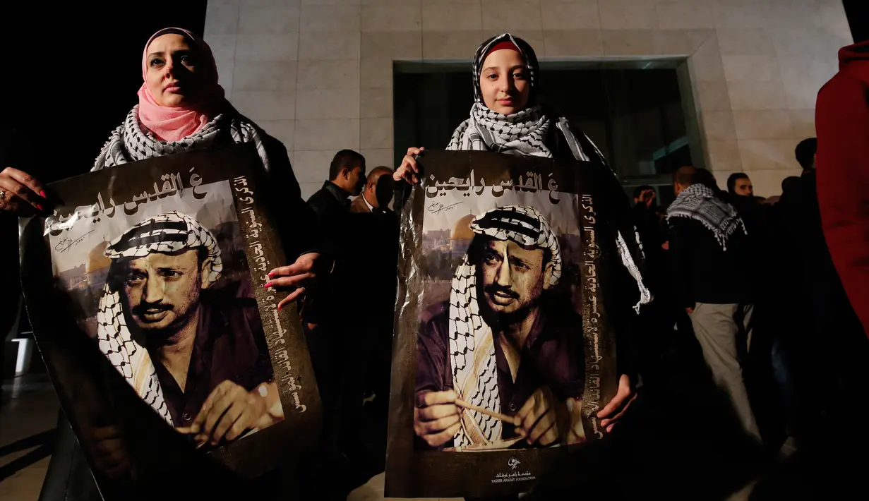 Warga Palestina memegang poster bergambar Yasser Arafat menjelang peringatan 11 tahun wafatnya mantan Presiden Yasser Arafat, di Ramallah, Tepi Barat, Selasa (10/11) malam waktu setempat. (AFP PHOTO / ABBAS Momani)