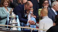 Pangeran William dari Inggris berjabat tangan dengan pelatih asal Spanyol milik Manchester City, Pep Guardiola, di samping trofi Piala FA setelah pertandingan final antara Chelsea melawan Manchester City di Stadion Wembley, London, pada 16 Mei 2026. Manchester City memenangkan pertandingan dengan skor 1-0. Gelar Piala FA ketiga pada era kepelatihan Guardiola tersebut mengakhiri dua kekalahan beruntun City di partai final. (Adrian Dennis / AFP)