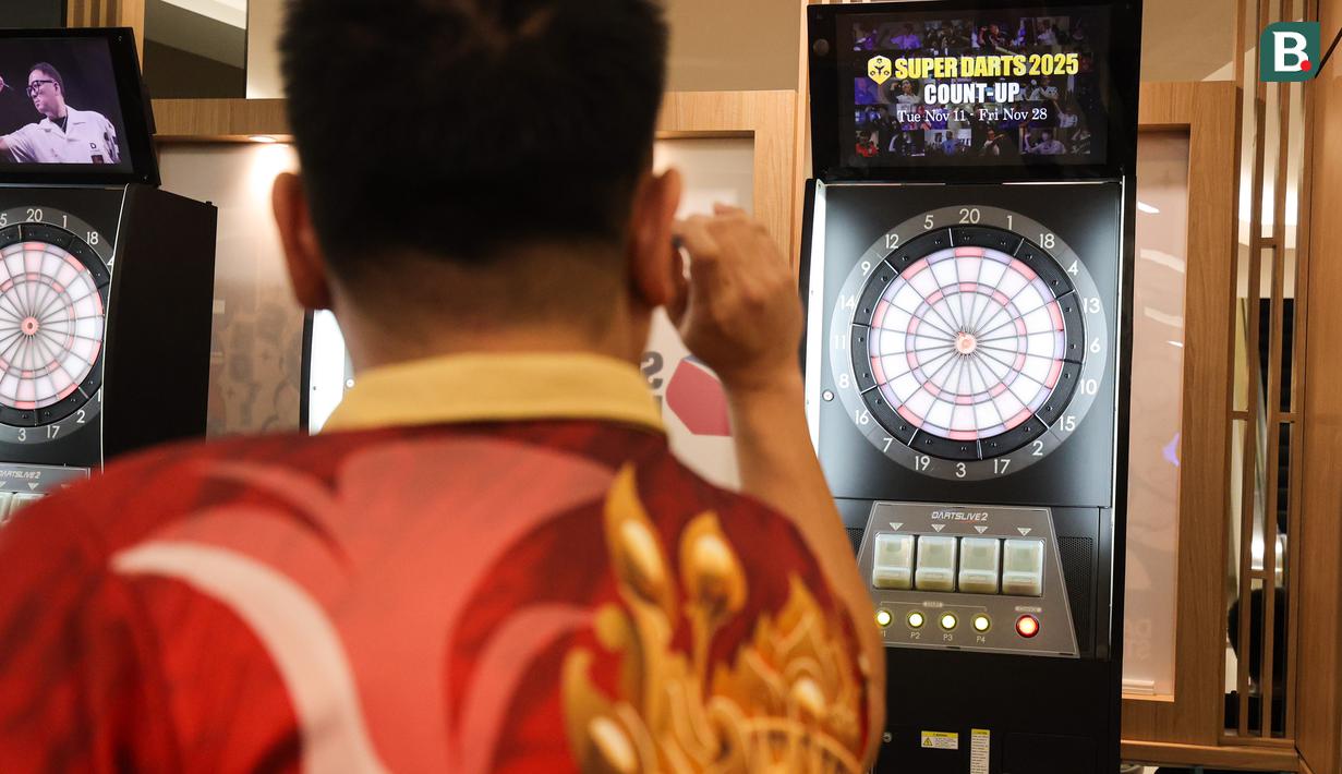 Pemain darts Indonesia Tirta Suparjo mencoba salah satu alat di acara peluncuran Darts Station di lantai F7 FX Sudirman, Senayan, Jakarta pada Sabtu (15/11/2025). (Bola.com/Abdul Aziz)