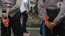 Petugas kepolisian memegang bunga mawar saat menjaga peserta aksi seruan damai di depan Kedutaan Besar Federasi Rusia, Jakarta, Rabu (30/3/2022). Aksi mengangkat tema "Setangkai Kembang dan Satu Nyanyian" dengan membawakan lagu Rayuan Pulau Kelapa versi bahasa Rusia. (Liputan6.com/Herman Zakharia)