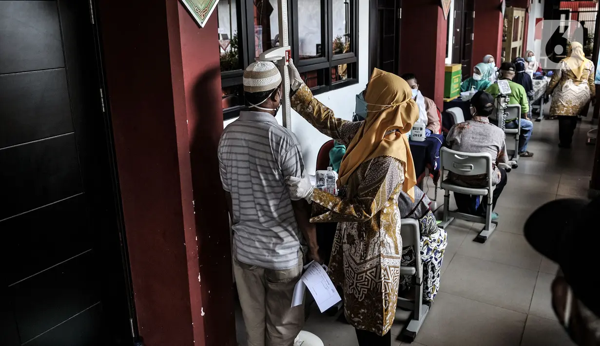 Petugas memeriksa tinggi badan warga lanjut usia (lansia) saat kegiatan vaksinasi COVID-19 di SDN 02 Sukapura, Cilincing, Jakarta Utara, Senin (22/3/2021). Pemkot Jakarta Utara menargetkan 1.500 lansia menerima vaksinasi COVID-19 per hari. (merdeka.com/Iqbal S. Nugroho)