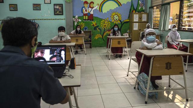 <span>Siswa mengikuti pembelajaran tatap muka (PTM) di sebuah sekolah di Surabaya, Jawa Timur, Senin (6/9/2021). Pemerintah kembali membuka sekolah di tengah pandemi COVID-19. (JUNI KRISWANTO/AFP)</span>