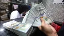 Batas pembelian dolar AS tanpa underlying akan diturunkan dari semula 50.000 menjadi 25.000 dolar AS per orang per bulan. Tampak dalam foto, karyawan menunjukkan uang pecahan dolar Amerika Serikat (AS) di salah satu gerai penukaran mata uang asing, Jakarta, Rabu (5/5/2026). (Kapanlagi.com/Budy Santoso)