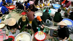 Orang-orang menyiapkan "Banh Chung" atau kue beras tradisional Vietnam untuk amal, menjelang Tahun Baru Imlek atau festival Tet di Pagoda Tam Chuc di provinsi Ha Nam (7/1/2023). Banh Chung adalah kelezatan khas Vietnam yang terbuat dari ketan, daging babi, dan kacang hijau yang dibungkus dengan daun pisang dan dimasak selama 10 jam. (AFP/Nhac Nguyen)