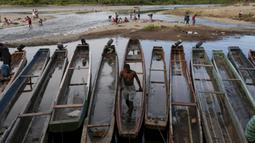 Seorang imigran berjalan di atas perahu yang ditambatkan di Sungai Tuquesa, Desa Bajo Chiquito, Provinsi Darien, Panama, 22 Agustus 2021. Para imigran dari Haiti dan negara-negara lain tiba di wilayah Panama setelah berjalan selama lima hari di Darien Gap. (ROGELIO FIGUEROA/AFP)