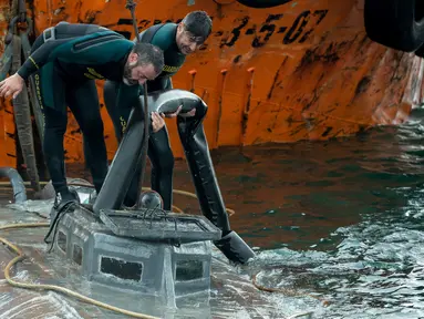 Penyelam dari anggota Garda Sipil Spanyol memeriksa kapal selam di perairan Aldan, Spanyol (26/11/2019). Kepolisian Spanyol menyita kapal selam berukuran 20 meter bermuatan berton-ton kokain asal Amerika Selatan di lepas pantai wilayah barat laut Galicia. (AFP/Lalo R. Villar)