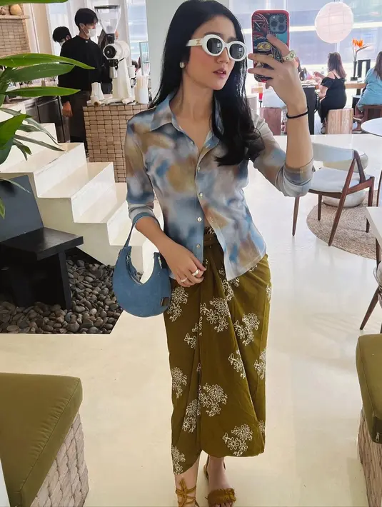 Gaya kece Febby memadukan tie-dye shirt dengan kain lilit dan kacamata hitam. [Instagram/febbyrastanty]