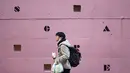 Seorang pria yang meletakkan masker wajah di bawah dagunya sambil makan makanan ringan berjalan melewati sekolah bahasa asing di Tokyo, Jepang,  Kamis (4 /2/2021). Tokyo mengonfirmasi lebih dari 730 kasus baru COVID-19 pada 4 Februari 2021. (AP Photo/Hiro Komae)